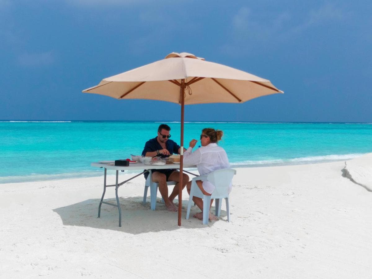 A table for two set on the sand at the water's edge