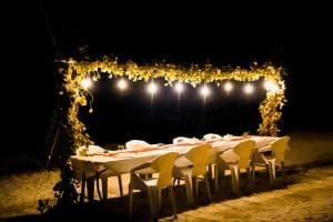 A long table laid out under festoon lights after dark